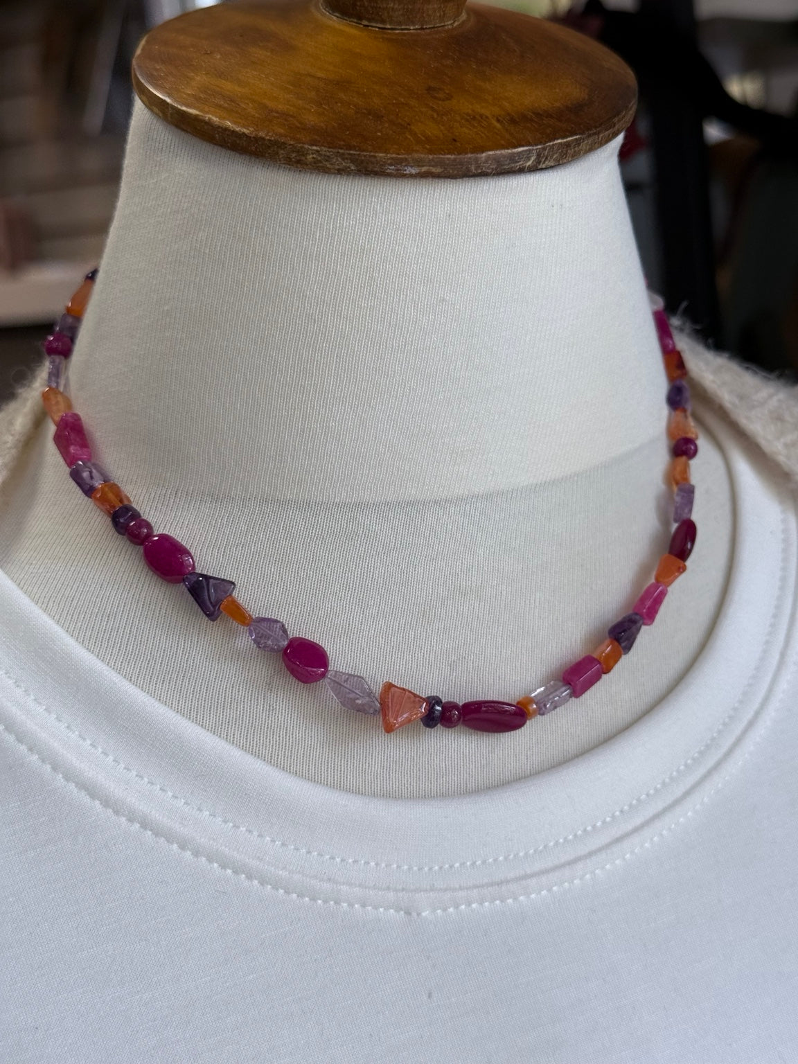 Collar artesanal de ágatas de colores mostrado sobre busto.