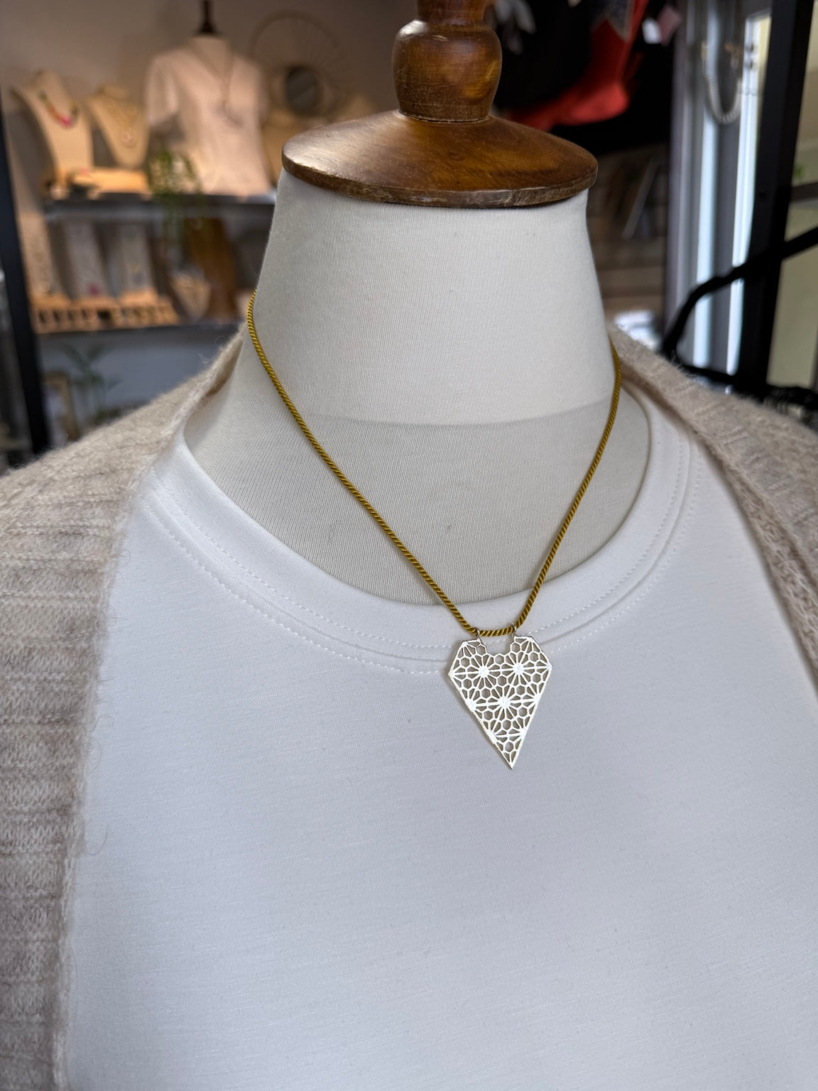 Collar artesanal con corazón calado mostrado sobre busto.