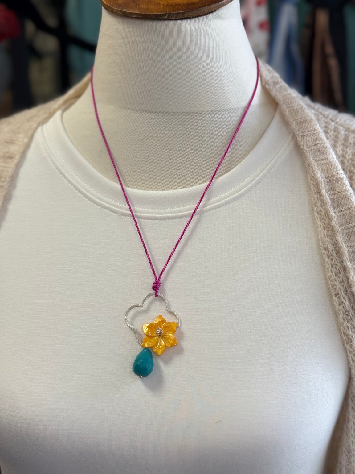Collar artesanal ajustable con flor de madreperla y jade azul turquesa mostrado sobre busto.