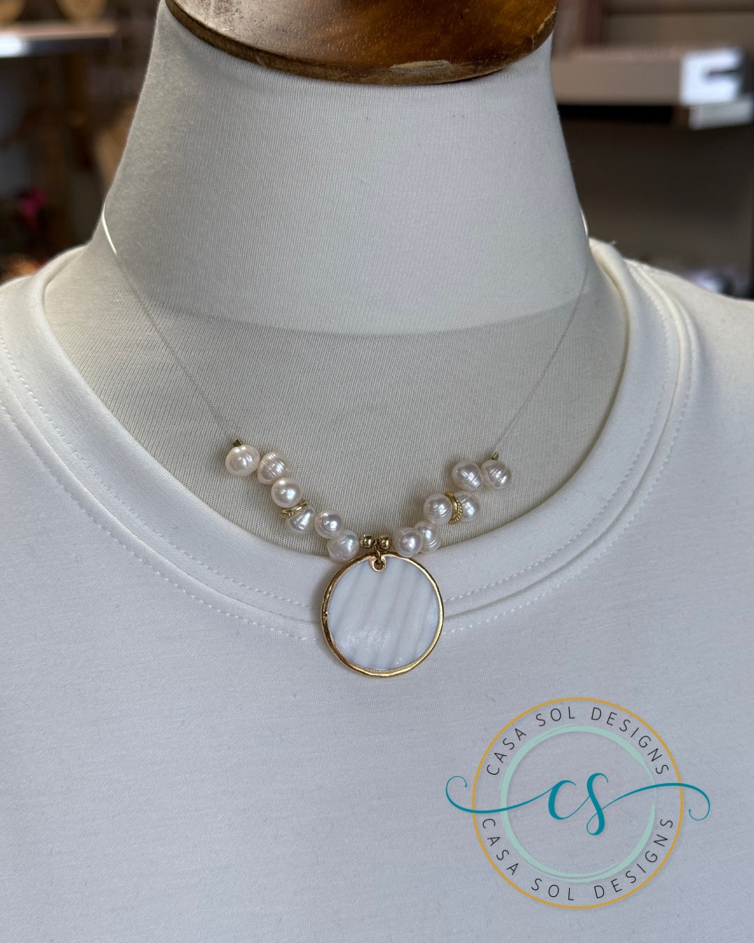 Collar ilusión con perlas de agua dulce y colgante de madreperla mostrado sobre busto.