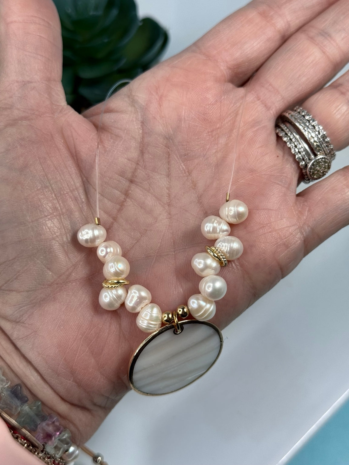 Detalle de collar ilusión con perlas de agua dulce y colgante redondo de madreperla.