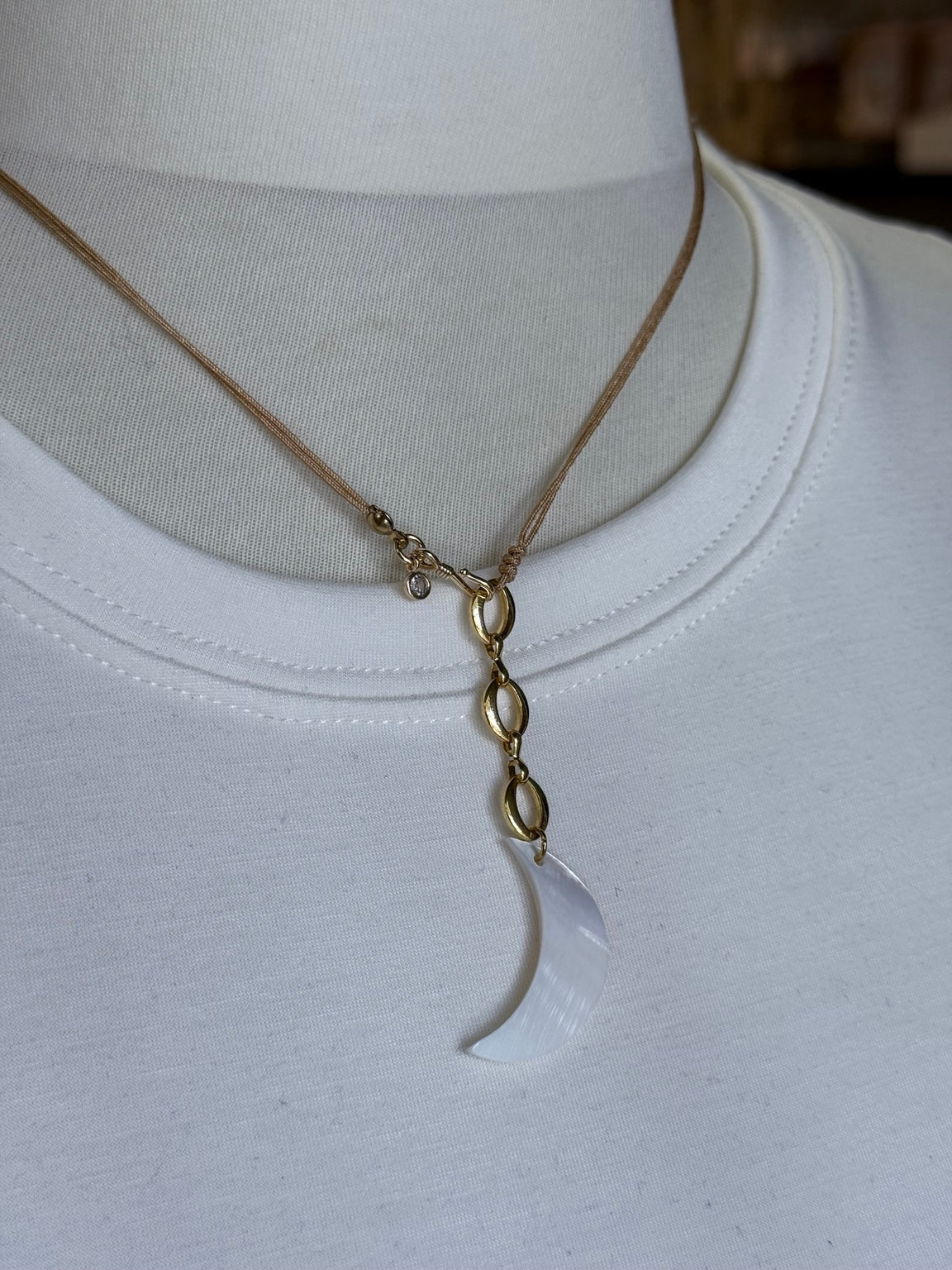 Collar luna de madreperla ajustable mostrado sobre busto.