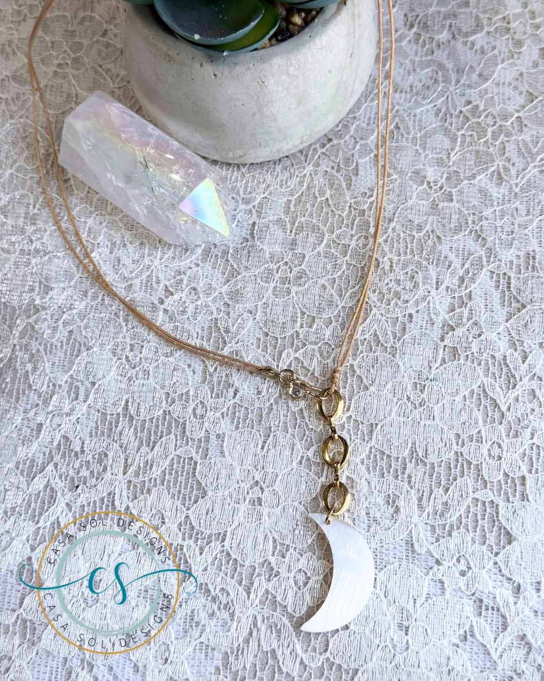 Collar artesanal con luna de madreperla y detalles dorados.