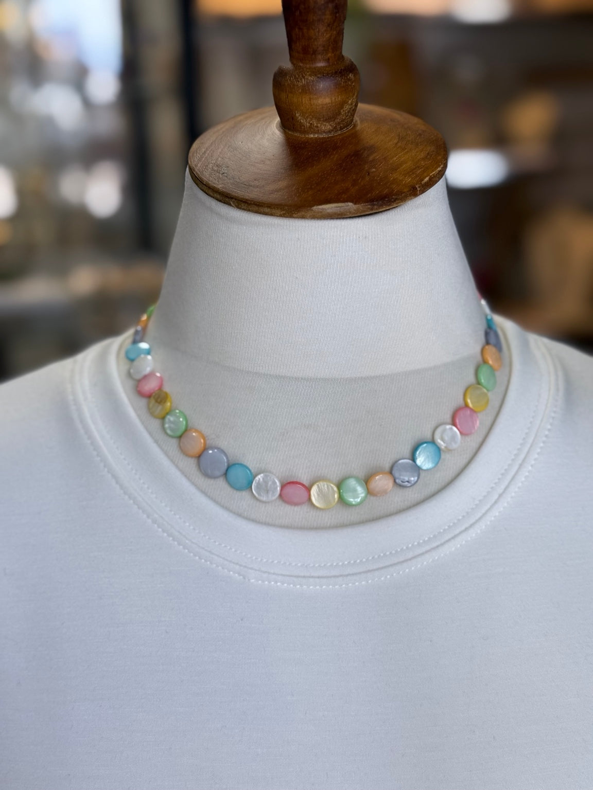 Collar de madreperla multicolor mostrado sobre busto.