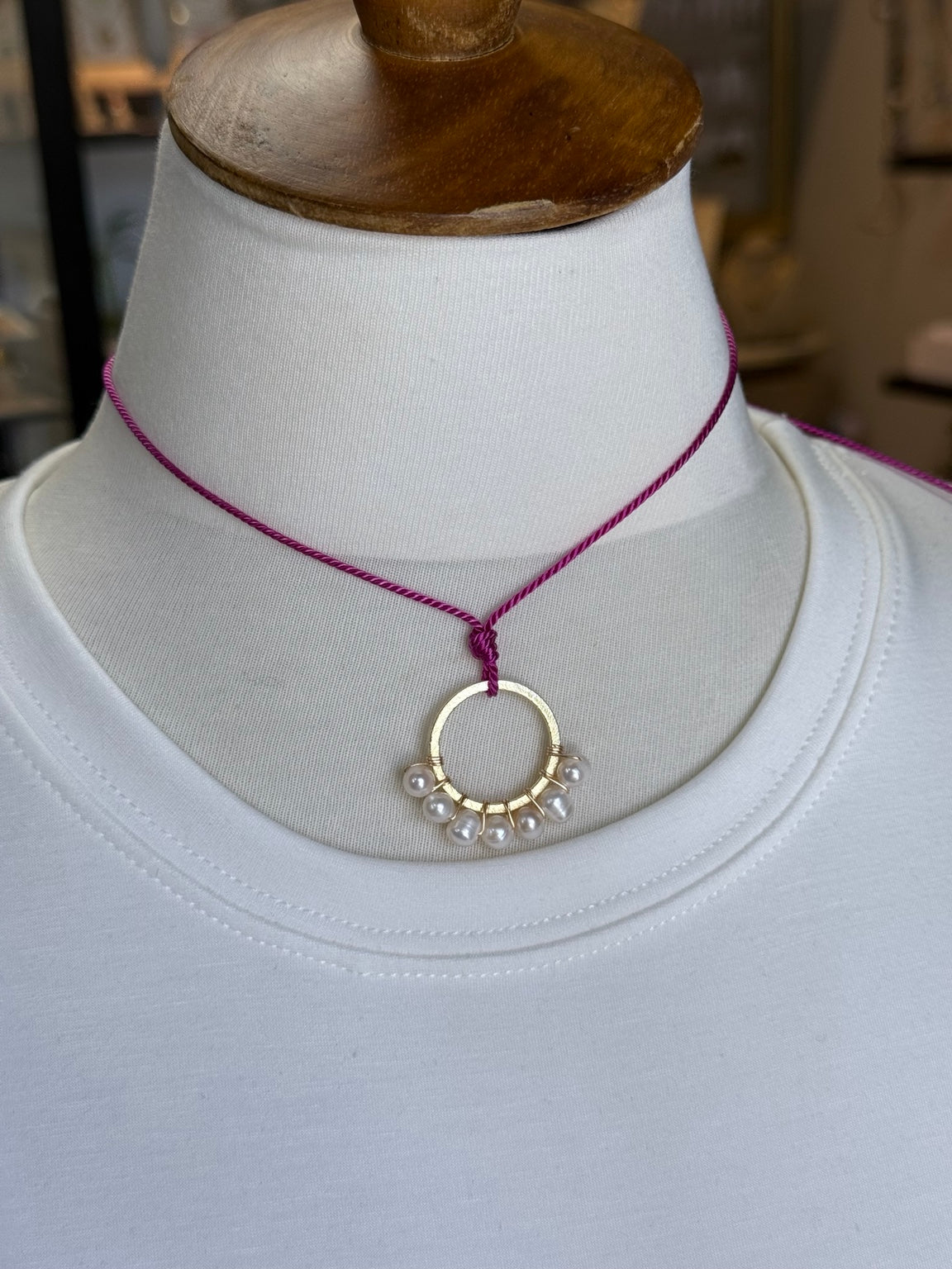 Collar ajustable de perlas de agua dulce y aro dorado mostrado sobre busto.