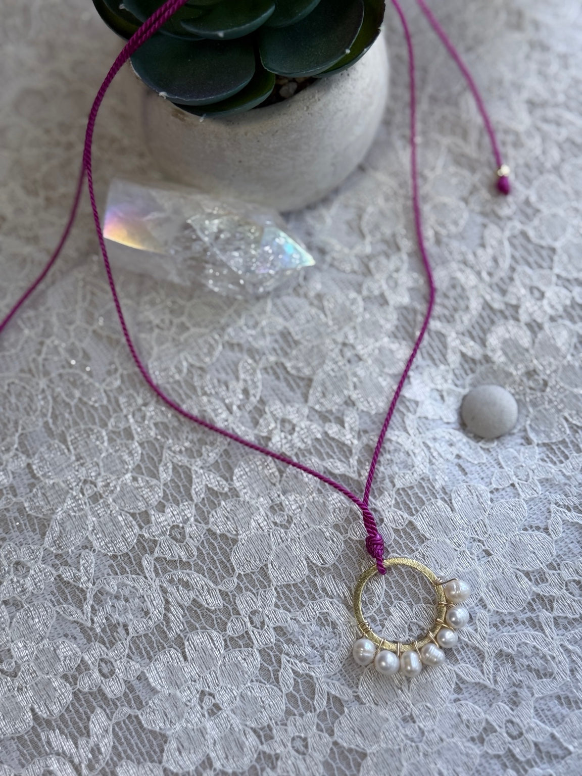 Detalle de collar ajustable con perlas de agua dulce y aro dorado.