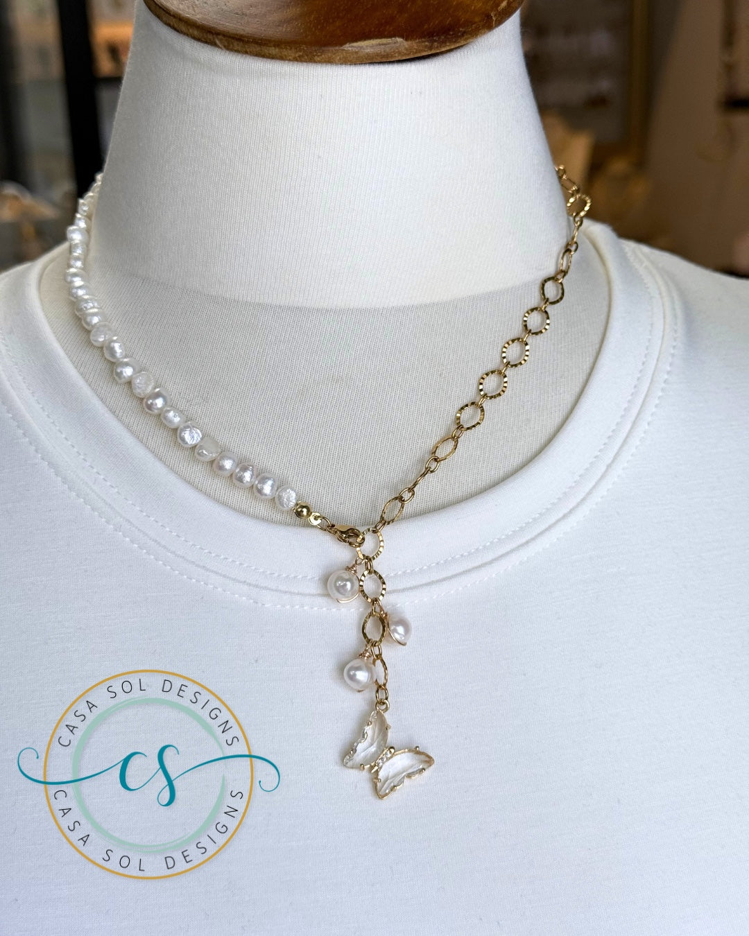 Collar de perlas de agua dulce con cierre frontal y dije de mariposa enchapado en oro.
