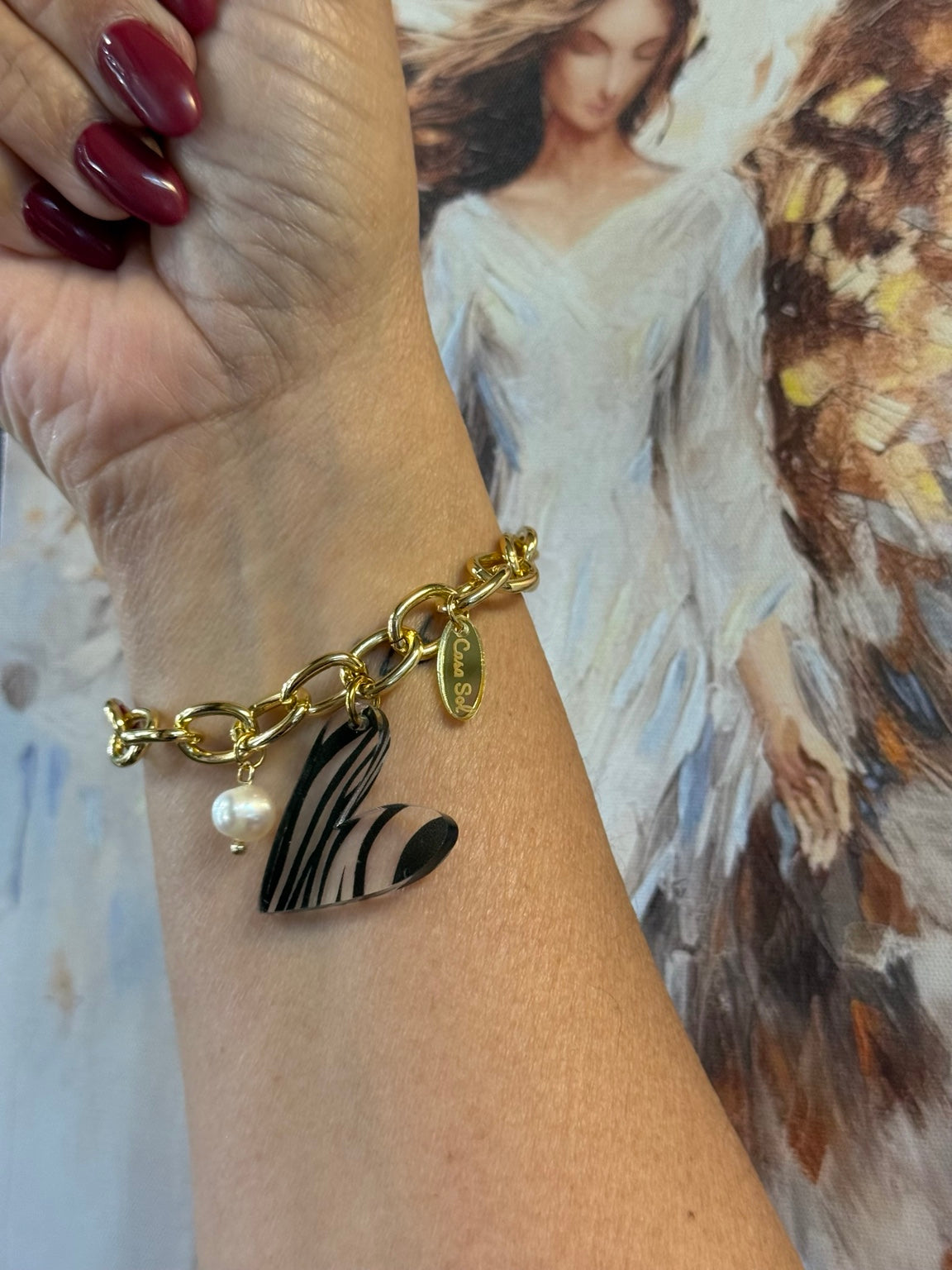 Pulsera ajustable con corazón de acrílico blanco y negro mostrada en la muñeca.