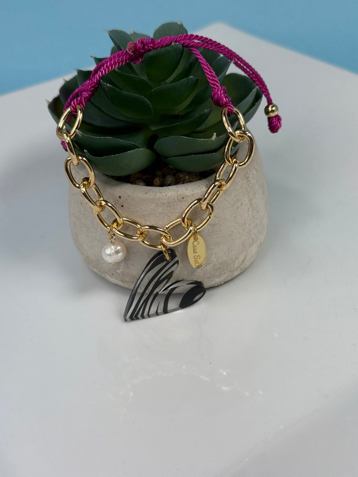 Pulsera ajustable con cordón frambuesa, cadena dorada y corazón de acrílico.