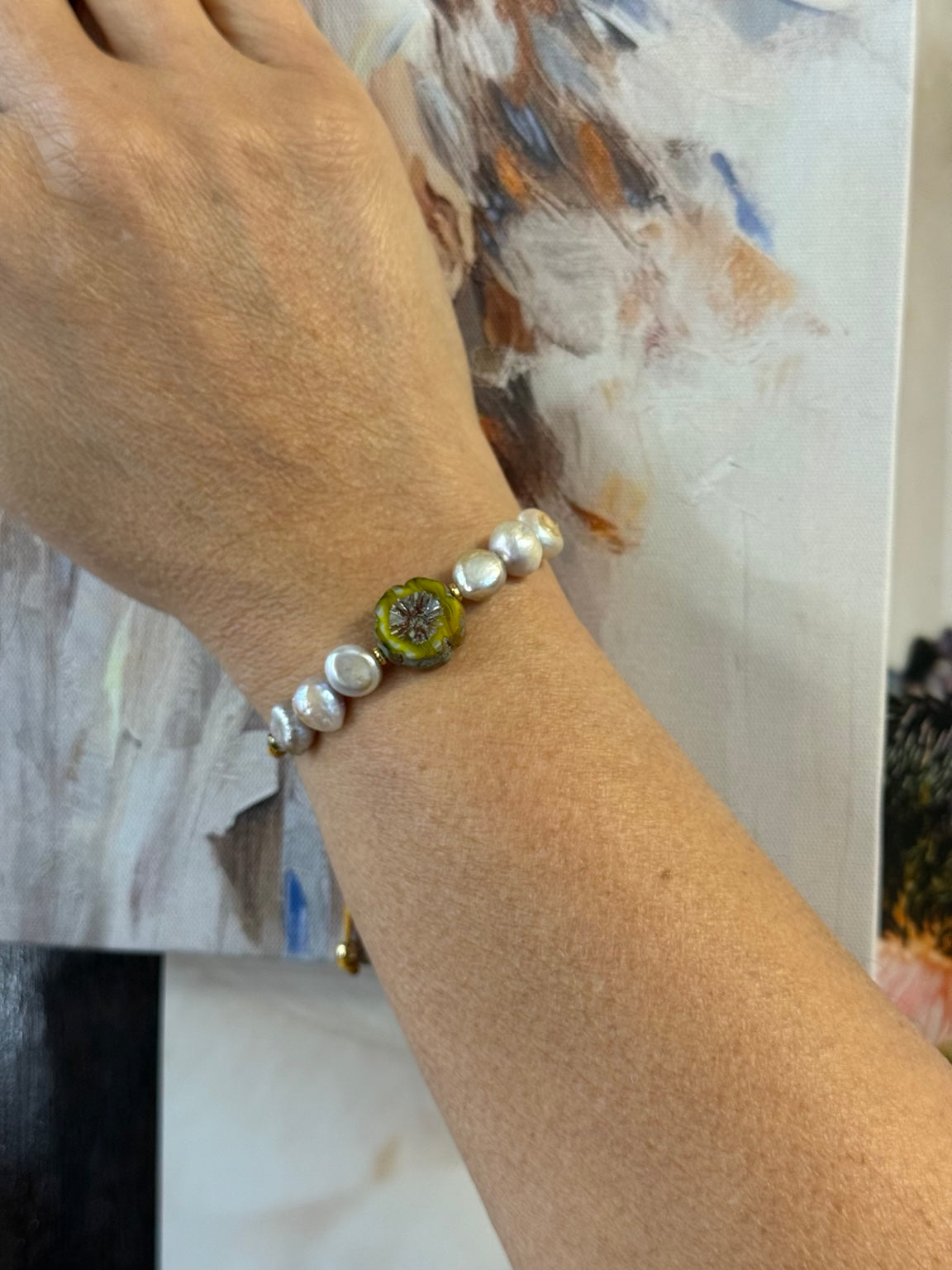 Pulsera ajustable de perlas de agua dulce malva y flor de cristal checo mostrada en la muñeca.
