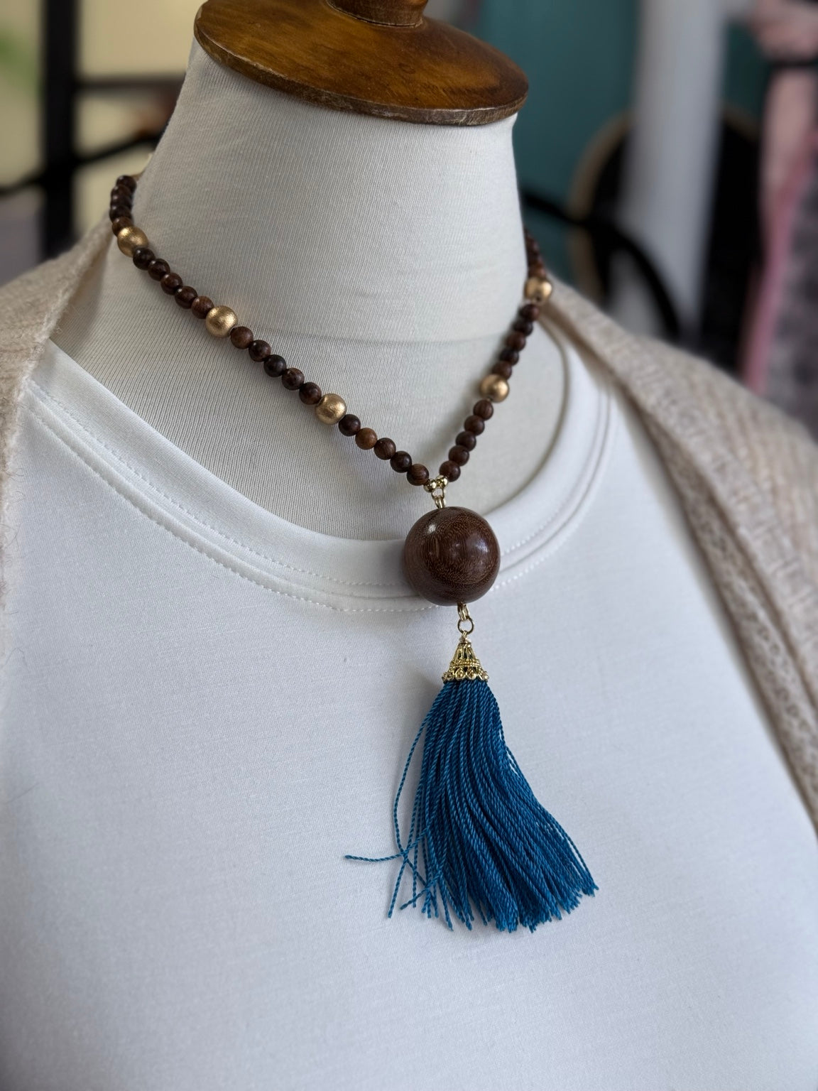 Detalle del collar de madera con borla turquesa.