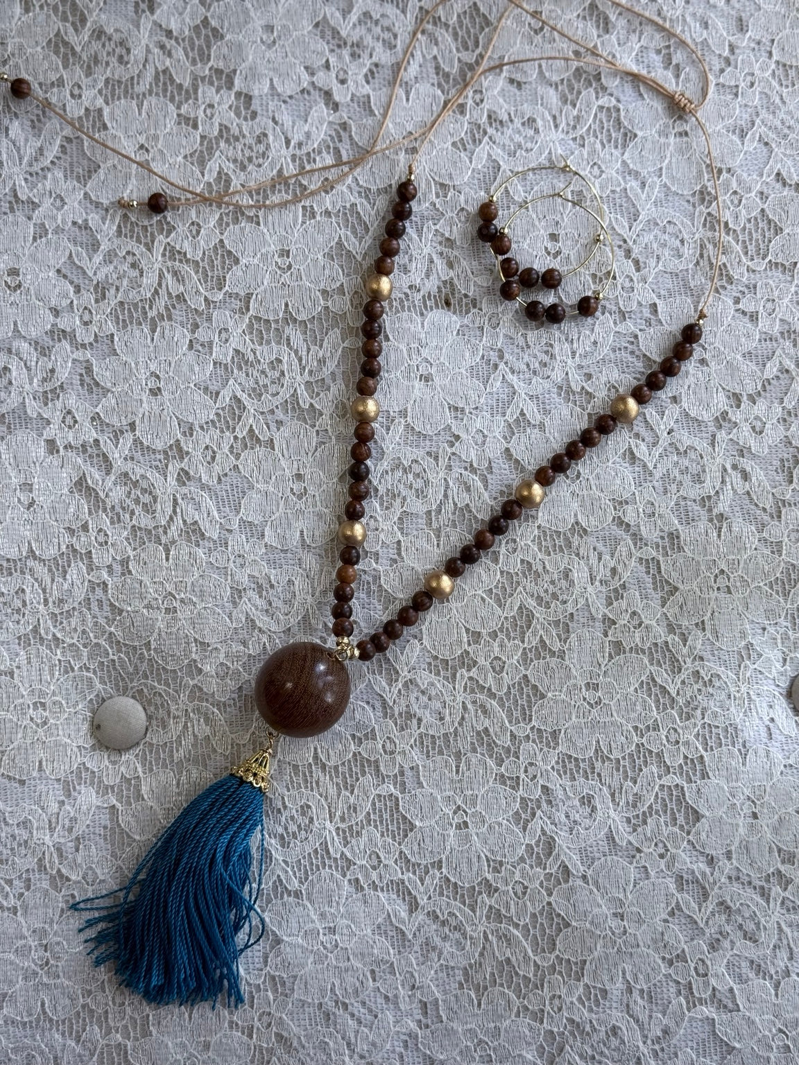Set artesanal de collar de madera con borla turquesa y pantallas tipo argolla.